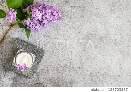 Flowers cosmetic composition with jar with natural face cream and lilac sprig on a grey textured background. Organic, plant based beauty products concept. Flat lay, copy space Flowers cosmetic composition with jar with natural face cream and lilac sprig on a grey textured background. Organic, plant based beauty products concept. Flat lay, copy space 128703387