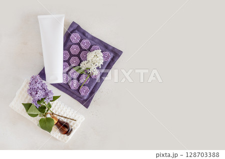 Spa relax flat lay with massage mat, dropper bottle with serum on white towel with lilac flowers and cosmetic tube on light grey background. Mock up of beauty product. Relaxing at home. Copy space Spa relax flat lay with massage mat, dropper bottle with serum on white towel with lilac flowers and cosmetic tube on light grey background. Mock up of beauty product. Relaxing at home. Copy space 128703388
