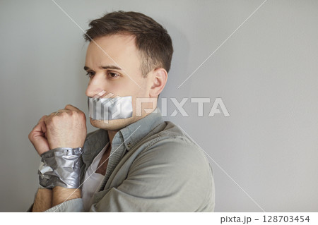 Male victim, young man suffer, mouth and hands taped keeping silent suffering, person harmed Male victim, young man suffer, mouth and hands taped keeping silent suffering, person harmed 128703454