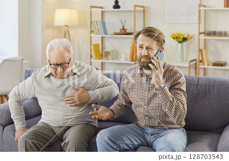 Young man calling the ambulance for his elderly father who's having a heart attack 128703543