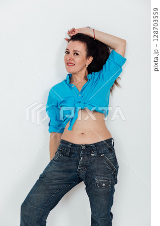 Beautiful brunette woman in jeans and blue shirt on white background 128703559