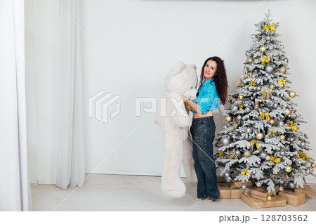 woman in jeans at Christmas tree with toys and gifts decorated for new year 128703562