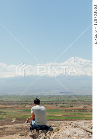 man sitting on a hill and looking mount man sitting on a hill and looking mount 128703663