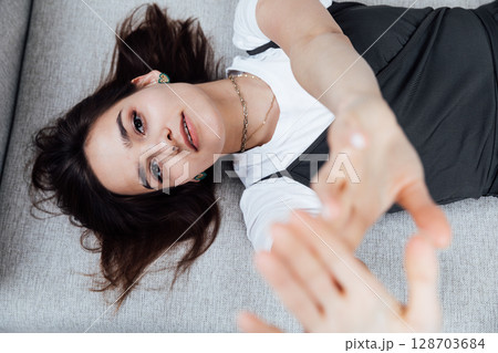 brunette woman lying on a gray office sofa in a white room 128703684