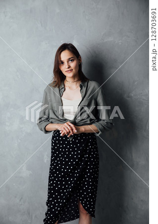 Beautiful brunette woman in summer dress and shirt on gray background 128703691