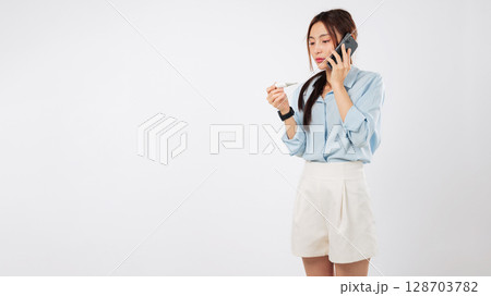 Asian woman feeling sick disease temperature taking a call, she worried and talking on phone about her fever, while holding thermometer, feeling so sick she needs doctor, isolated white background Asian woman feeling sick disease temperature taking a call, she worried and talking on phone about her fever, while holding thermometer, feeling so sick she needs doctor, isolated white background 128703782