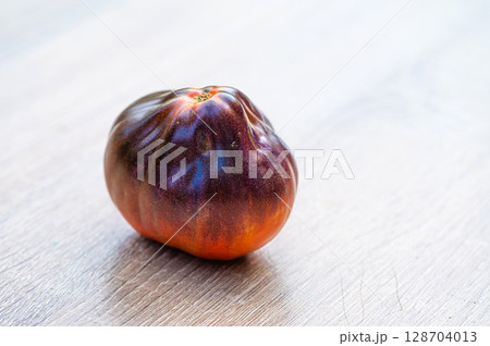 fresh picked multicolored striped and streaky black, purple, and red tomatoes on a wooden table fresh picked multicolored striped and streaky black, purple, and red tomatoes on a wooden table 128704013