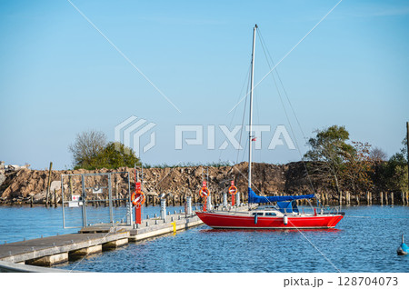 Yacht at a wooden platform in the port of Engure on the coast of the Baltic Sea 128704073