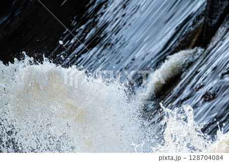 close up of flowing water, rapid water splashes of an white water river or stream, bubbly water close up of flowing water, rapid water splashes of an white water river or stream, bubbly water 128704084