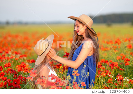 beautiful young woman with girl in straw hats in poppy field, happy family having fun in nature beautiful young woman with girl in straw hats in poppy field, happy family having fun in nature 128704400