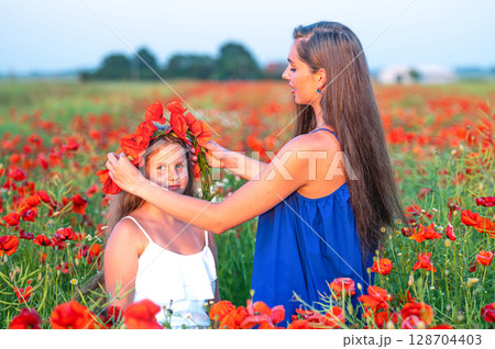 elegant young woman with child girl in poppy field, happy family having fun in nature, summer time 128704403