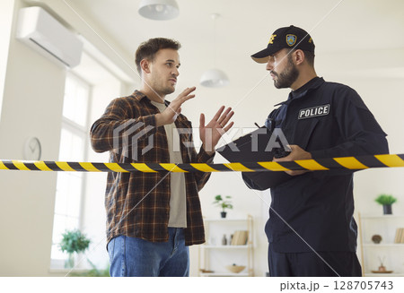 Portrait of a police man officer talking to witnesses or interrogating a young worried man. 128705743