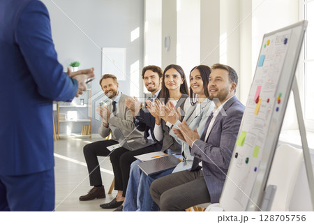 Business team applauding speaker during presentation, showing approval and interest in discussion. Business team applauding speaker during presentation, showing approval and interest in discussion. 128705756