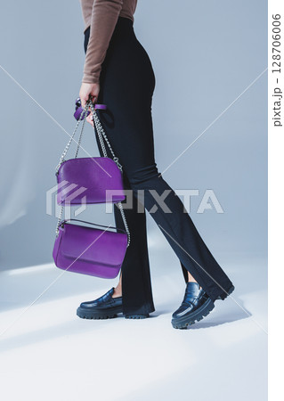 A purple leather bag in a girl's hand. Woman with luxury bag. 128706006