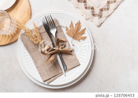 White autumn boho table setting with dry leaves. White autumn boho table setting with dry leaves. 128706453