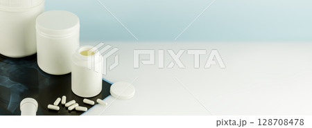 Calcium Ca supplements for Bone human health. Bone and joint health. Mockup of supplements for skin, bones and joints. White bottles with capsules and X-ray film. Banner size, copy space Calcium Ca supplements for Bone human health. Bone and joint health. Mockup of supplements for skin, bones and joints. White bottles with capsules and X-ray film. Banner size, copy space 128708478