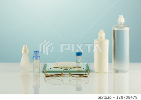 Night contact lenses. Ophthalmology concept with eyeglasses, containers with contact lenses, moisturizing eye drops and clean solutions. Advertising contact lenses for vision. Optical store and eye ca 128708479