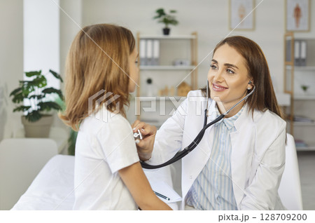 Pediatrician checking kid patient in clinic, kind female doctor, nurse holding stethoscope examining 128709200
