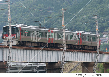 【広島・可部線】緑の山々を背に鉄橋を走るJR227系電車（Red Wing） 128709282