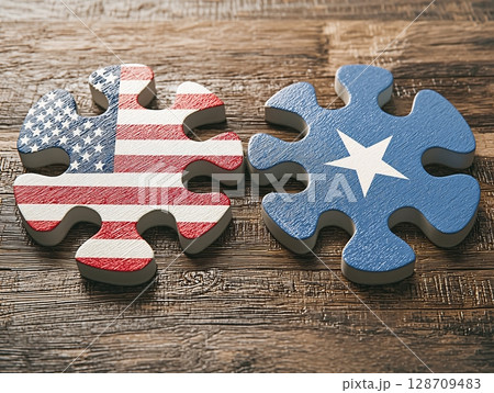United States Flag Puzzle Piece Connecting with Lone Star Puzzle Piece on Wooden Surface 128709483