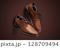 Elegant Brown Leather Dress Shoes with Laces on Brown Background 128709494