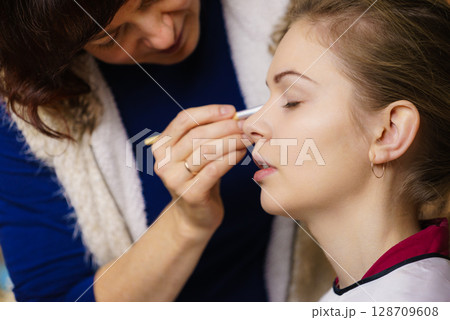 Woman getting eyes make up done by artist 128709608
