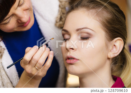 Woman getting eyes make up done by artist 128709610