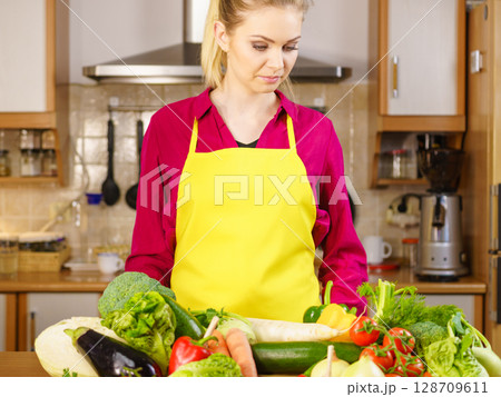 Woman in kitchen having many vegetables 128709611