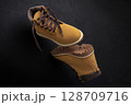 Yellow Hiking Boots with Rugged Soles on Dark Background 128709716