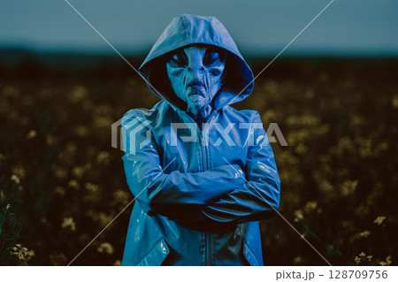 Spooky Alien Under Green Neon Light. Scary Mask, Vinyl Smooth Raincoat. Ufo 128709756