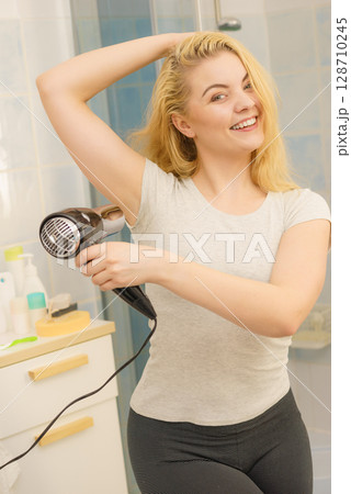 Woman drying sweat stains using hair dryer 128710245