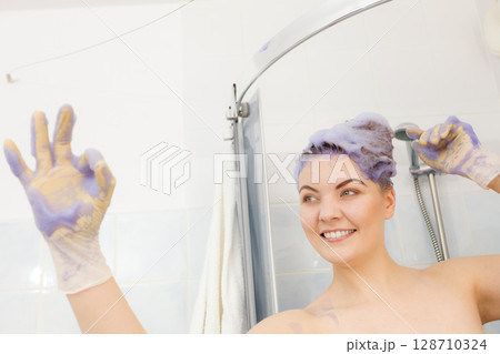 Woman applying toner shampoo on her hair Woman applying toner shampoo on her hair 128710324