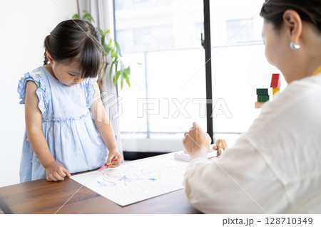 クレヨンでお絵描きを楽しむ女の子の知育シーン クレヨンでお絵描きを楽しむ女の子の知育シーン 128710349