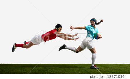 Two female rugby players in action on a green field against white background Two female rugby players in action on a green field against white background 128710564