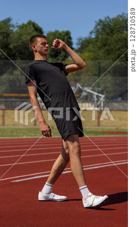 Athlete maintains balance on track beneath a sunny sky wearing casual sportswear 128710589