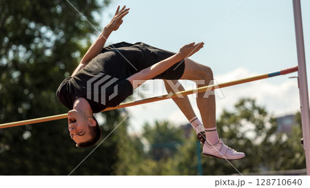 Athlete airborne in high jump at outdoor competition Athlete airborne in high jump at outdoor competition 128710640