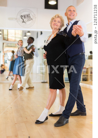 Elderly woman learning ballroom dancing movements in pair Elderly woman learning ballroom dancing movements in pair 128711238