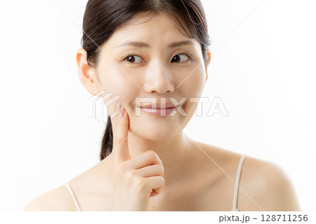 肌の悩みを気にする若い女性の表情（白背景） 128711256