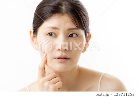 肌の悩みを気にする若い女性の表情（白背景） 128711258