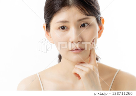 肌の悩みを気にする若い女性の表情（白背景） 128711260