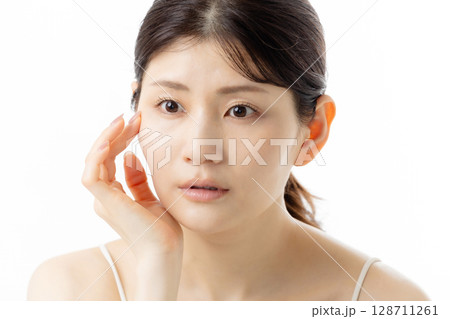 肌の悩みを気にする若い女性の表情(白背景) 肌の悩みを気にする若い女性の表情(白背景) 128711261