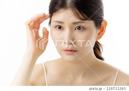 肌の悩みを気にする若い女性の表情（白背景） 128711263