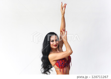 Brunette in Red Dress Performing Eastern Dance Movements Against a White Background 128711267
