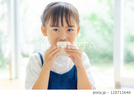 おにぎりを食べる女の子 128711640