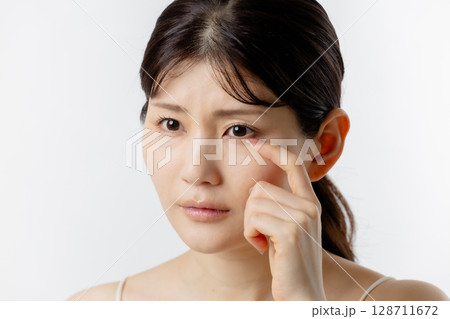 目元の悩みを気にする若い女性(白背景) 目元の悩みを気にする若い女性(白背景) 128711672