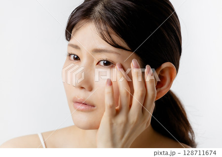 目元の悩みを気にする若い女性（白背景） 128711674