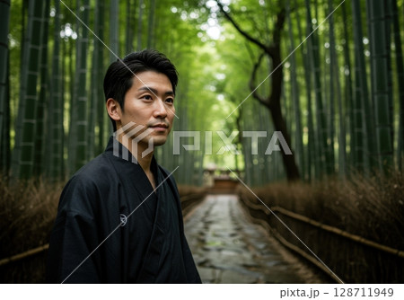 Portrait of a young asian man in a black kimono in a beautiful bamboo forest in Japan 128711949