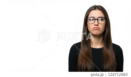 Grumpy young woman in glasses pouting with an offended expression on a white background 128712063