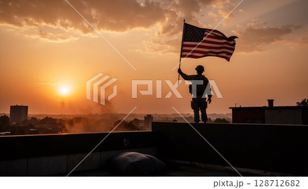 Silhouette of Soldier Holding American Flag Against Dramatic Sunset Sky Over City Landscape 128712682