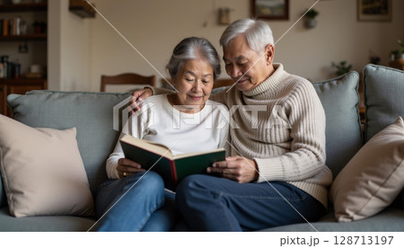 Elderly Couple Enjoying a Quiet Moment Together While Reading on a Cozy Sofa 128713197